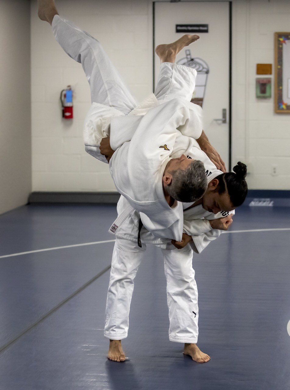 Two judoka practicing a standing throw in a dojo