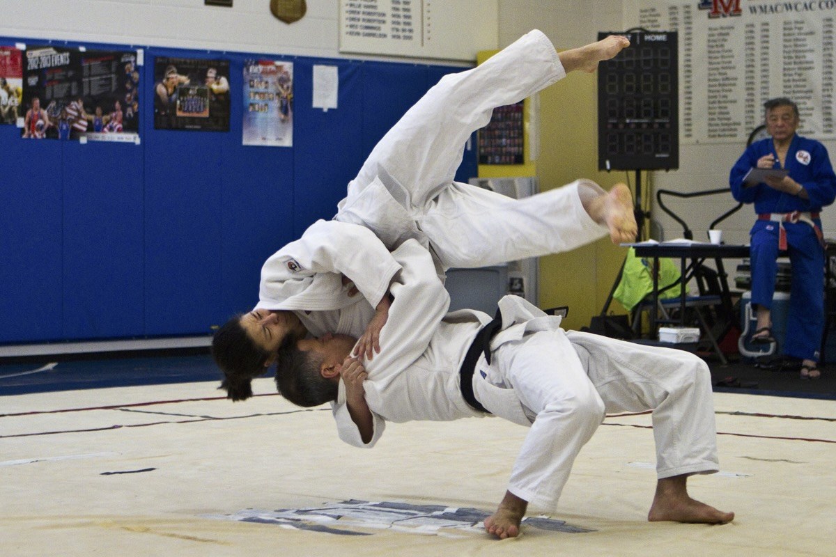 Two judoka demonstrating a throw in a gym