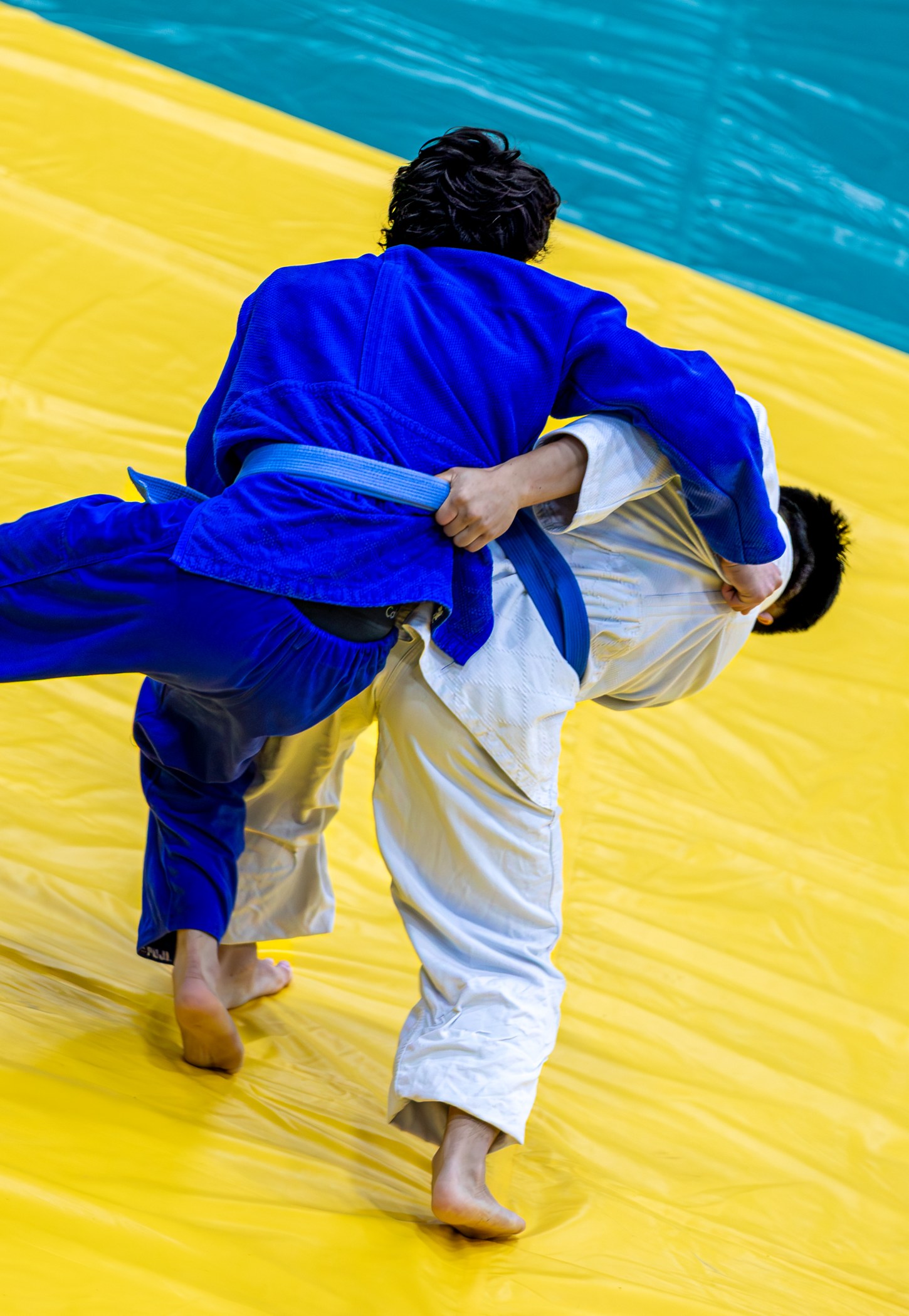 Judoka in blue and white working through a gripping exchange