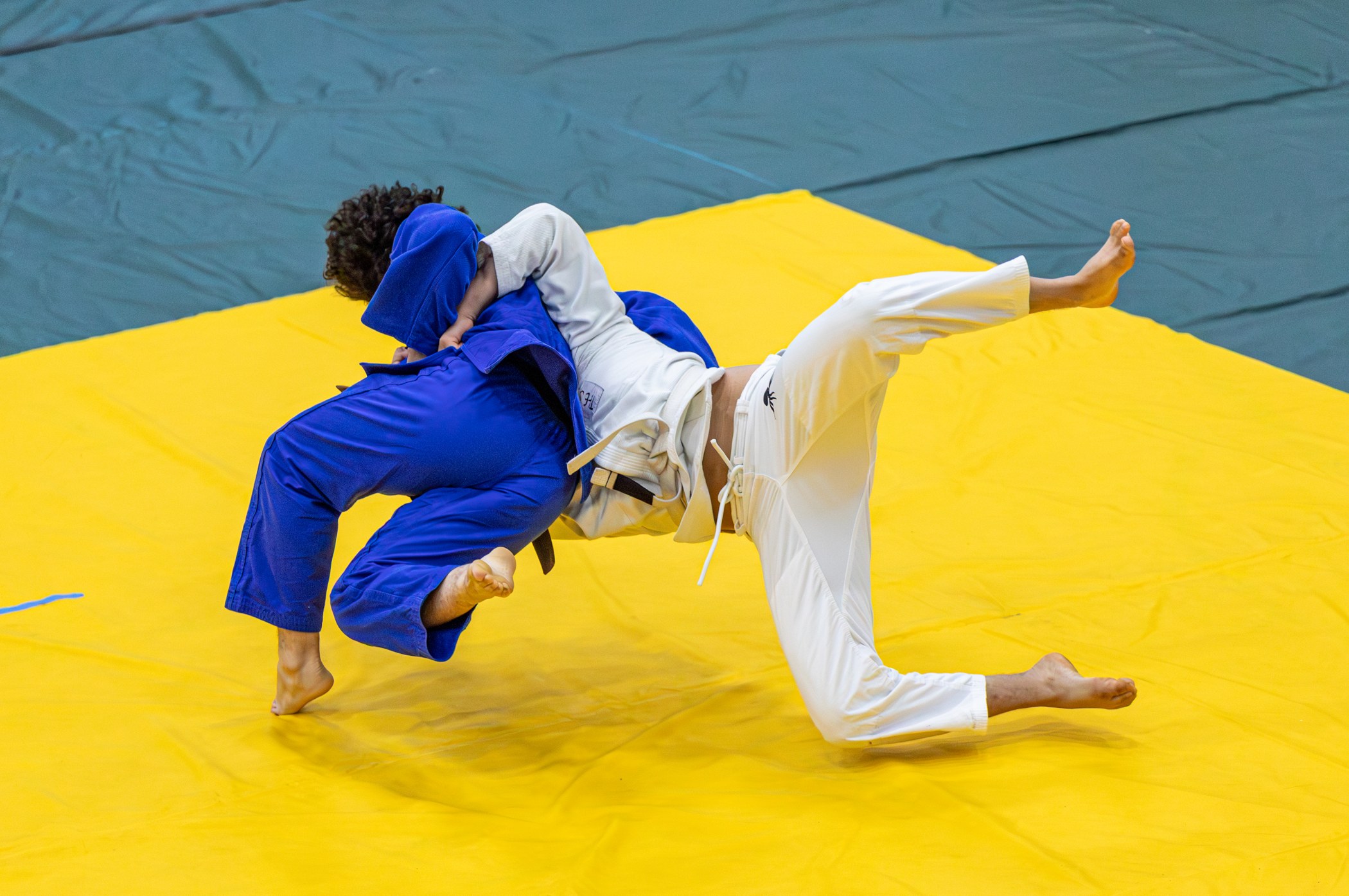 Two judoka moving through a dynamic throw